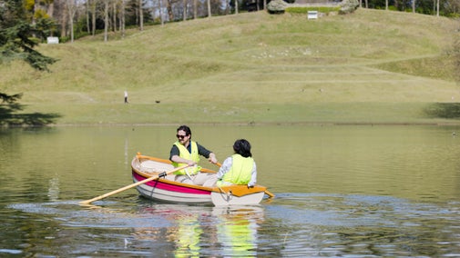 Two people wearing life vests sitting on a row bow with Claremont's amphitheatre in the background